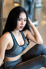 Obraz na płótnie Canvas Fitness Asian women sitting in sport gym interior and fitness health club with sports exercise equipment Gym background.