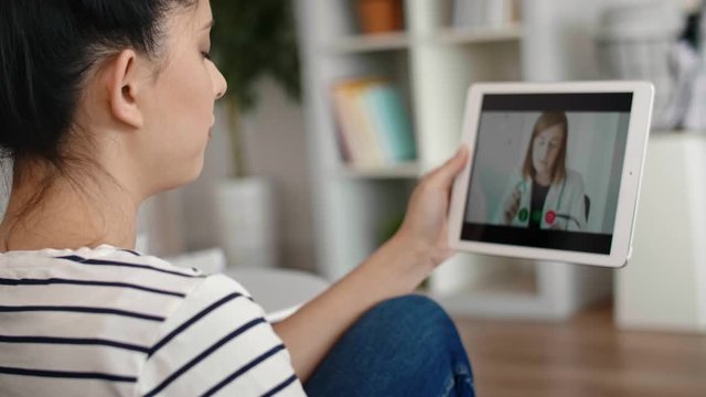 Handheld video of young woman having video conference with doctor