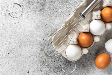 Eggs in a tray on the kitchen table. White and brown eggs with a whisk in the tray. Chicken eggs...