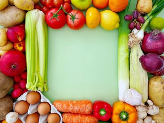 Vibrant and colorful fruit and vegetables create a square frame with copy space against a pastel green background. Fresh and organic food from a local farmers market. Flat lay summer salad ingredients