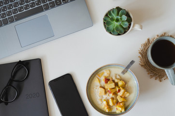 White flatlay of desktop with phone mockup and coffee cup, morning breakfast, scedualing in 2020, oatmeal, oats