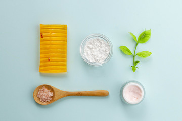 Organic cosmetics with natural ingredients: soap, face cream, alginate mask, sea salt on light blue background, top view