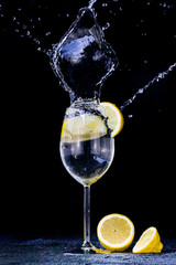 a lemon splashing in a glass of alchohol