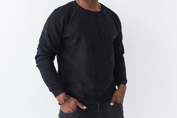 Close-up of black man dressed in jeans and sweatshirt on white background. Street fashion and...