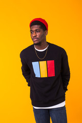 Handsome African American man posing in black sweatshirt on a yellow background. Youth street fashion photo with afro hairstyle.