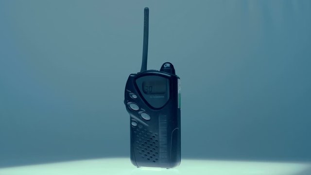An amateur walkie-talkie stands on a white luminous table and rotates. The second base will call it, the request icon is appears on the display