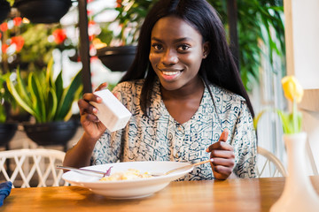 African woman adding salt to food in restaurant.