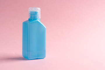 Alcohol antiseptic for hands in a blue plastic pocket container on a pink background. Copyspace. The idea of disinfection against coronavirus