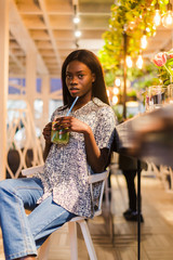 African american woman drinking cocktail lemonade in cafe at the bar.