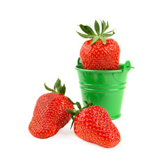 Fresh strawberry in a tiny green bucket and two ripe strawberries isolated on white background. Close-up studio shot. Organic fruit harvesting season.