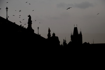 Black and white detail of the Charles Bridge with statues and tower during sunset. Magical picture of the medieval gothic bridge and baroque statues in the historical center of Old Town, Prague