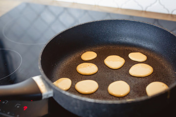 Tiny pancake cereal quarantined trending food. mini pancakes are fried in a pan in the kitchen. Cooking process. Live photo fry