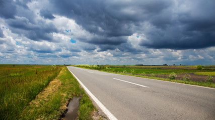 Asphalt road through the valley with cloudy sky