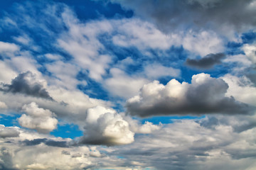 Cloudscape. Blue sky and grey clouds. Sunny day. Cumulus clouds.