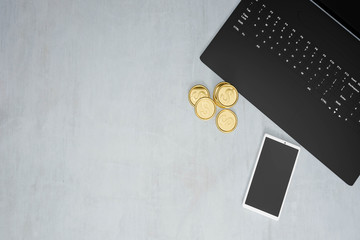 top view of modern concrete work desk with black laptop, golden coins and smartphone with copy space, 3d rendering