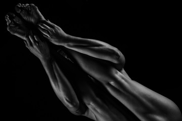 Girl yogi performs exercises on a black background. The flexibility of the female body. Asana. Relief of the muscles. Figures from the body.