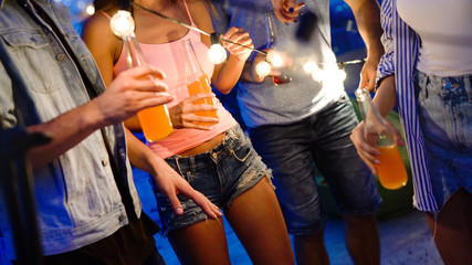 Friends enjoying cocktails at a party. Group of happy people having fun, dancing on a rooftop