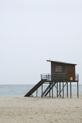 Framed wooden lifeguard tower on empty beach and overcast day