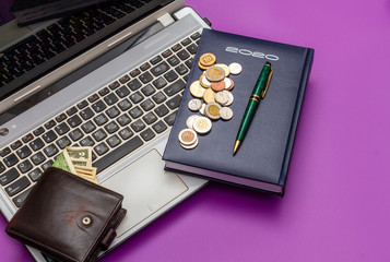 Diary 2020, a wallet with dollars, small coins and a pen are on the computer.