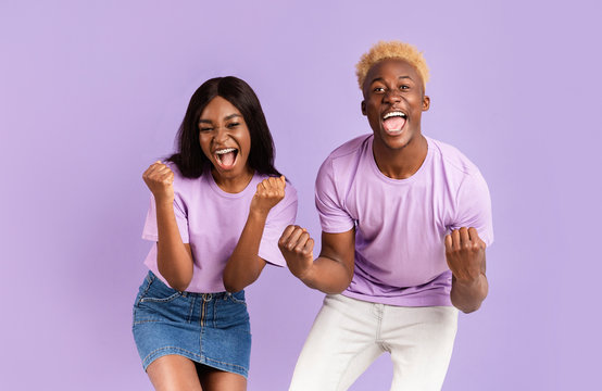 African American couple shouting OMG, happy over victory or success on lilac background