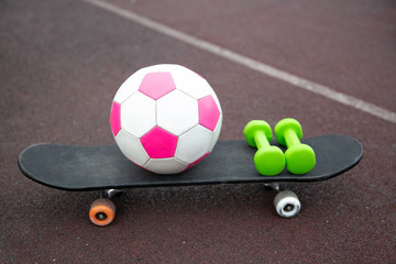pink soccer ball, dumbbells, skateboard isolated on the treadmill. The concept of sports lifestyle.