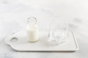 Dalgona coffee cooking step by step recipe. Step 6. Adding ice cubes to the glass and pouring milk on white background. Side view.