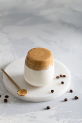 Iced Dalgona Coffee, a trendy fluffy creamy whipped coffee in a glass on white background with coffee beans. Side view, copy space. Cafe menu