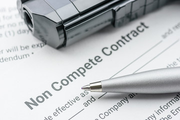 Blue pen, a gun or a pistol on a non compete contract. Noncompete contract is an agreement between...