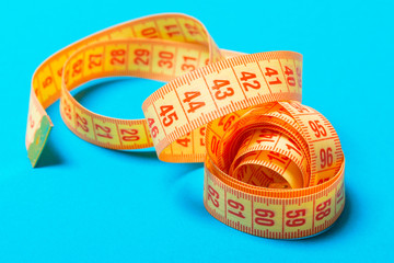 Perspective view of spiral measuring tape on blue background. Close up of slimming concept