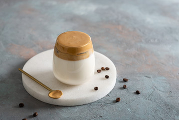 Dalgona Coffee, a cool fluffy whipped coffee. Latte espresso with coffee foam in tall glass on white background. Side view, copy space. Cafe menu, recipe