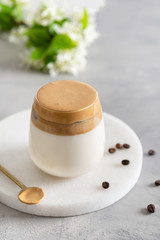 Homemade Dalgona coffee in glass with coffee beans on white table. Recipe popular Korean drink latte with foam of instant coffee. Created new drink during Quarantine and self-isolation.