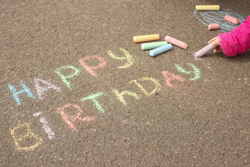 Happy birthday written in colored crayons on the sidewalk