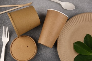 A set of eco-friendly utensils with green leaves on a concrete background. The concept of eco-friendly utensils. From above.