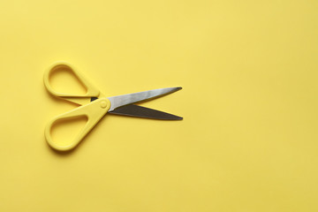 Yellow stationery scissors on yellow surface flat lay