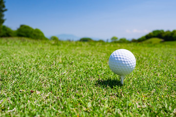Golf Ball on tee at the teeing area. Golf course with a rich green turf beautiful scenery.