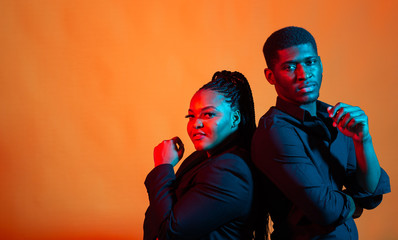 Dark neon portrait of young african american man and woman. Red and blue light.