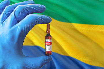 Gabon flag with Coronavirus Covid-19 concept. Doctor with blue protection medical gloves holding a...
