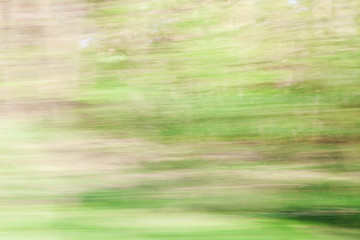 Defocused background of window view of moving car. Blurry image of grass, sky and trees