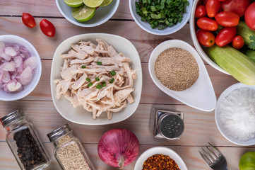 Boiled chicken cut into pieces in a white dish on a wooden table.