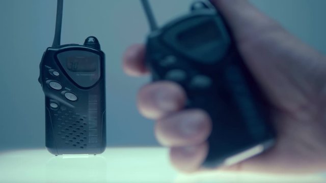 An amateur walkie-talkie is standing on a white luminous table, the second base in the hand will call it, the request icon is appears on the display. Includes audio. Contains audio. Closeup 