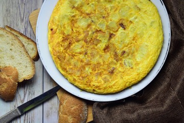 Potato omelette, typical dish from Spain, with slices of baked bread