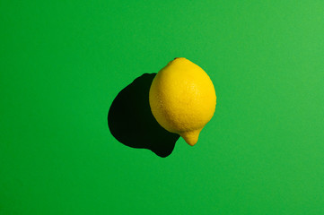 Yellow lemon on a green background with hard light