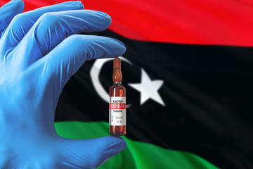 Libya flag with Coronavirus Covid-19 concept. Doctor with blue protection medical gloves holding a...