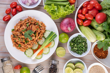 Spicy minced chicken on a white plate complete with cucumber, lettuce and side dishes.