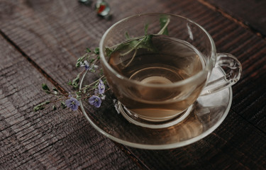 glass cup of tea with herbs. flowers in the cup.