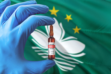 Macao flag with Coronavirus Covid-19 concept. Doctor with blue protection medical gloves holding a vaccine bottle. Epidemic Virus, Cov-19, Corona virus outbreaking.
