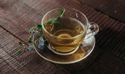 glass cup of tea with herbs. flowers in the cup.