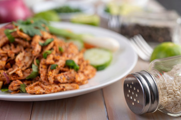 Spicy minced chicken on a white plate complete with cucumber, lettuce and side dishes.
