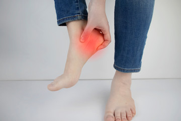 Woman suffering from heel pain. Inflammation or sprain of the tendon in the foot, heel spur, bursitis. The concept of diseases and pains in the leg - obrazy, fototapety, plakaty