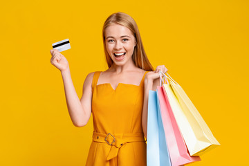 Fototapeta na wymiar Sales And Discounts. Excited Girl Holding Shopping Bags And Credit Card
